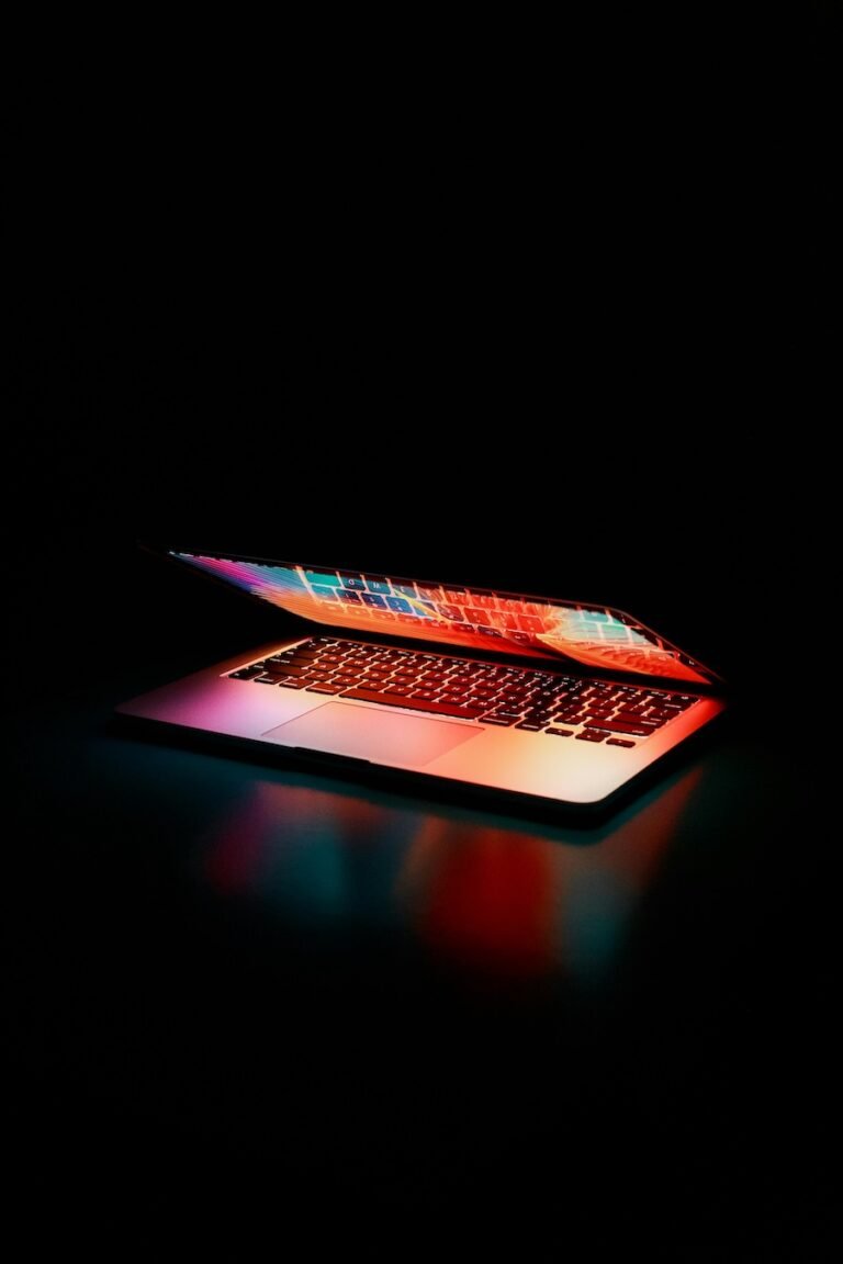 Partially open laptop with colorful screen against a dark black backdrop.